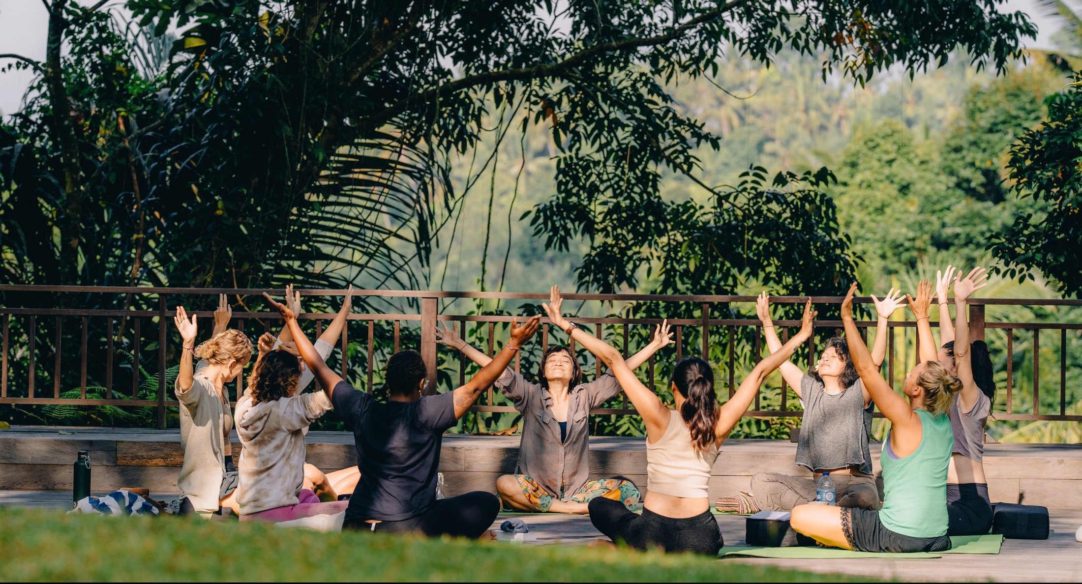 Retreat group in a sunrise yoga circle over the Bali jungle